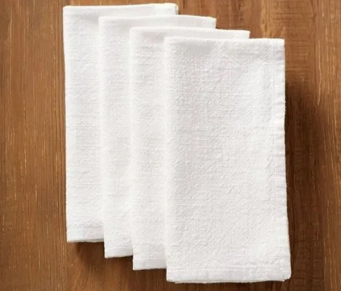 Folded cotton textiles napkins in neutral colors on a wooden table