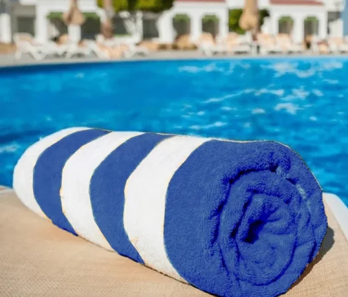 a rolled up blue and white towel next to a pool